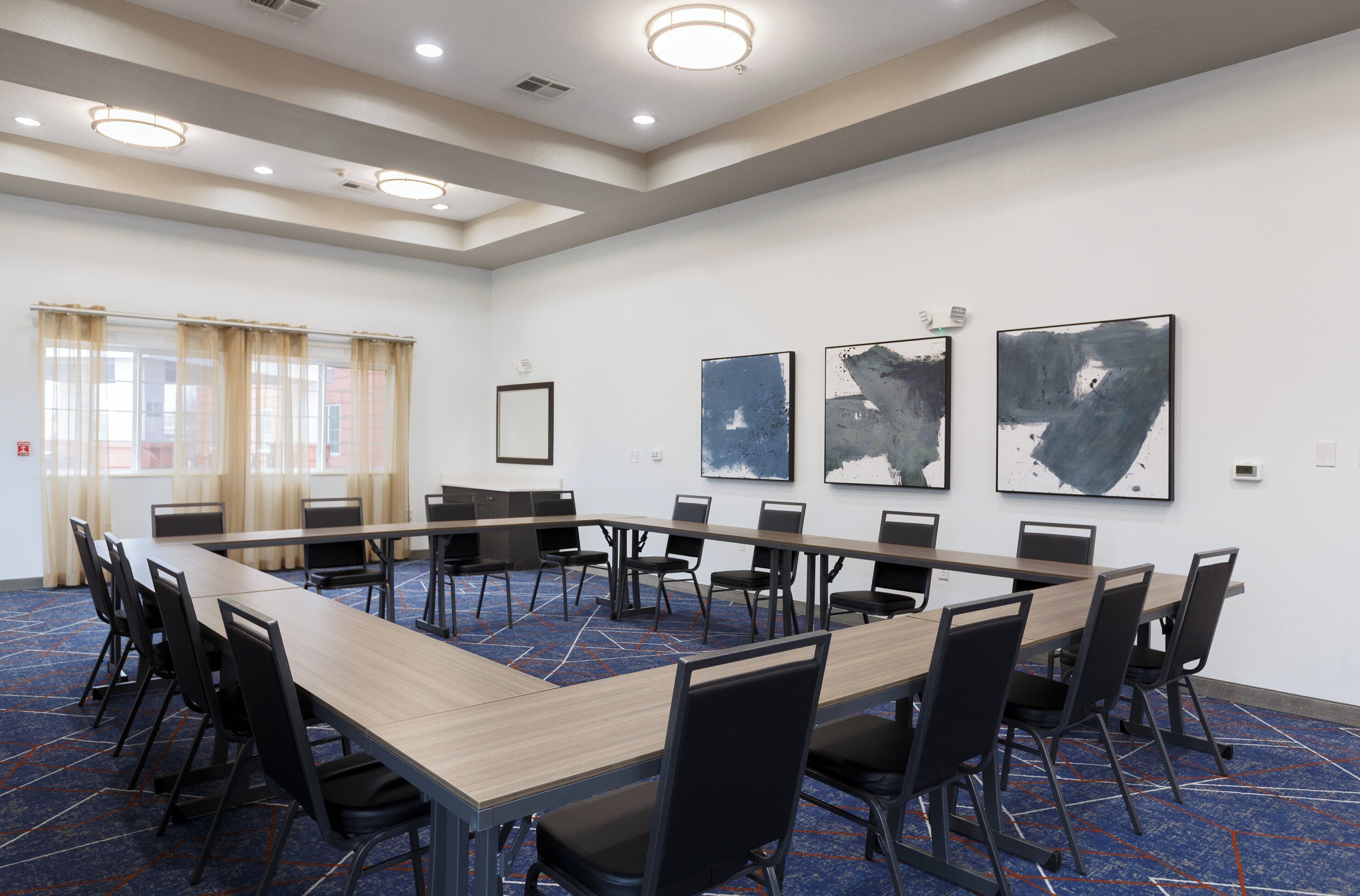 A conference room with a long table, black chairs, and abstract art on the walls.