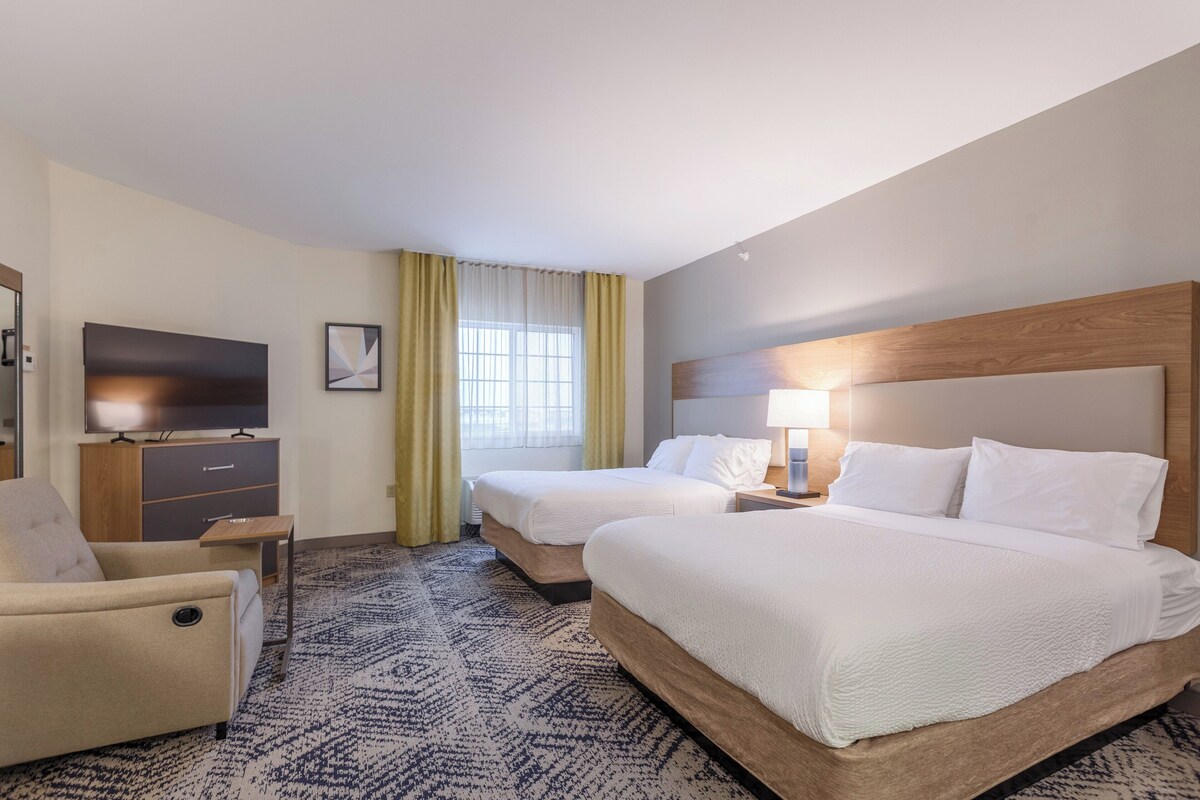A hotel room with two beds, a TV, a desk, and a chair.
