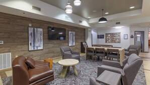 Un espace de détente moderne avec des canapés en cuir, une table ronde en bois et des fauteuils gris.