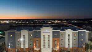 Un hôtel doté d’une entrée principale, de nombreux espaces de stationnement et offrant une vue sur les environs au crépuscule.
