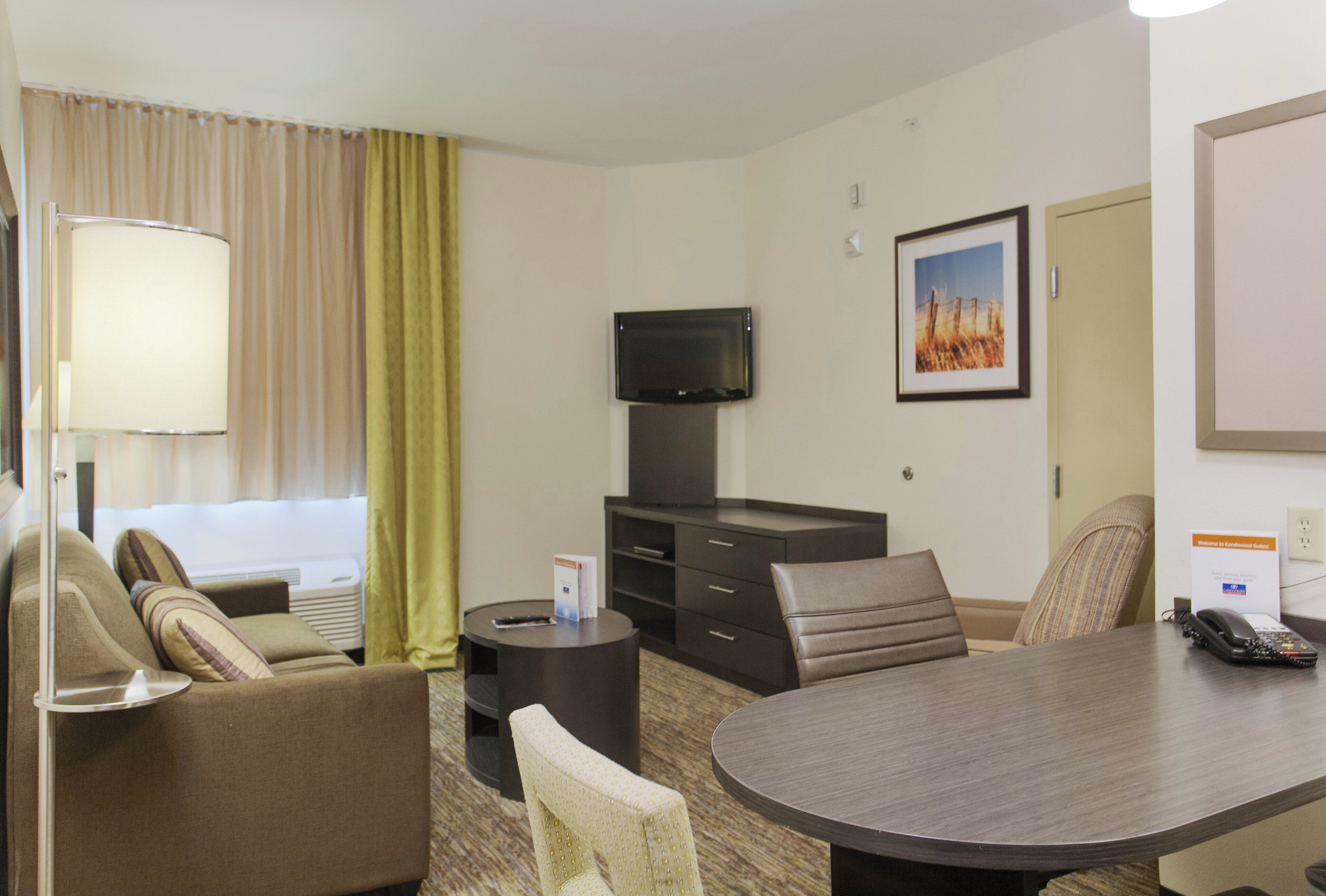 Une chambre d’hôtel avec un lit, un bureau, une chaise, une télévision, une lampe et un tableau au mur.
