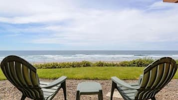 Two Adirondack chairs facing a beach with ocean views.