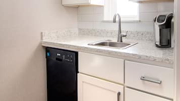 A compact kitchen with a dishwasher, a sink, and a coffee maker.