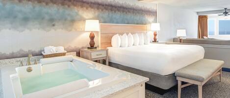 Een hotelkamer met een groot bed, een zithoek, een badkuip en uitzicht op de stad.