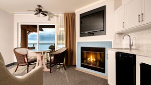 A modern kitchen with a fireplace, a dining area with a view of the ocean, and a ceiling fan. - Hallmark Resort - Newport (Newport)