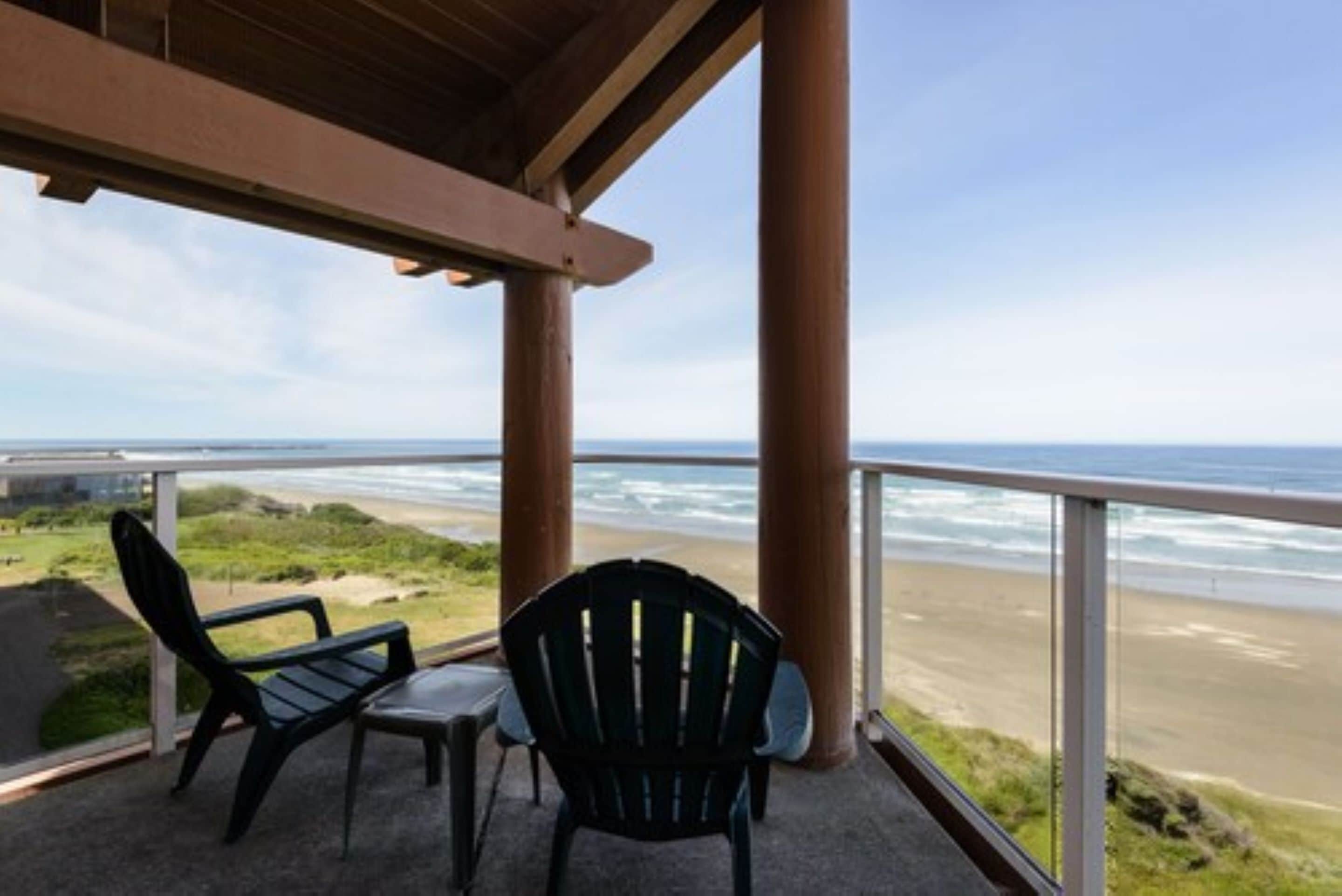 Un espacio de estar al aire libre cubierto con dos sillas Adirondack mirando a la playa.