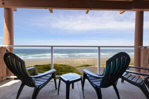 A balcony with two Adirondack chairs and a small table, overlooking a beach and ocean. - Hallmark Resort - Newport (Newport)