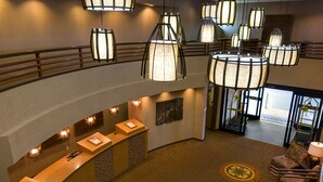 A hotel lobby with a reception desk, multiple hanging lamps, and a seating area with a leopard print chair. - Hallmark Resort - Newport (Newport)