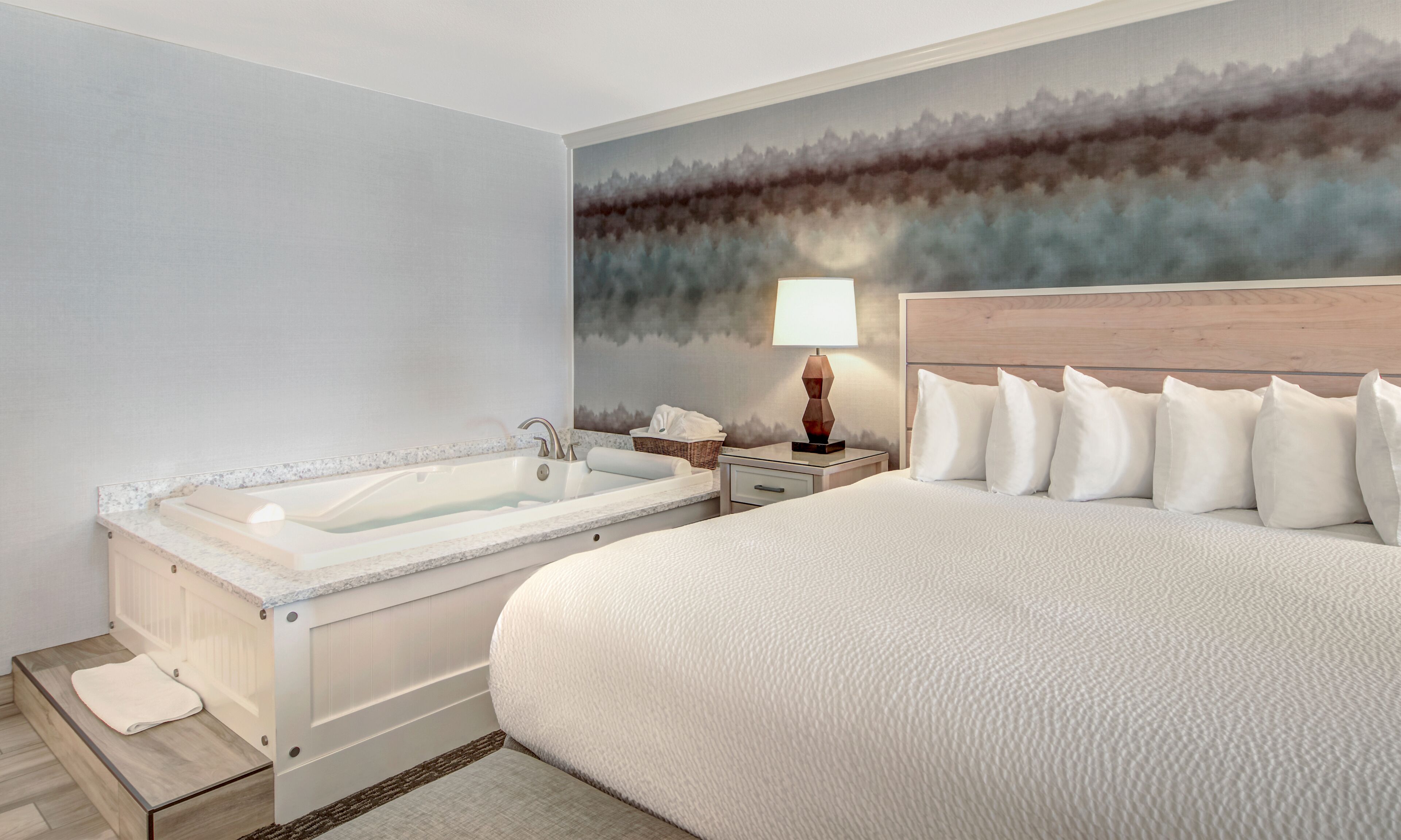 Ein Hotelzimmer mit einem großen Bett, einer Badewanne, einem Nachttisch und einem Wandbild.