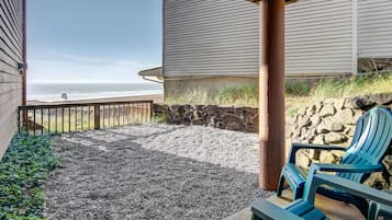 Um pátio com vista para o oceano, uma parede de pedra e um deck de madeira.