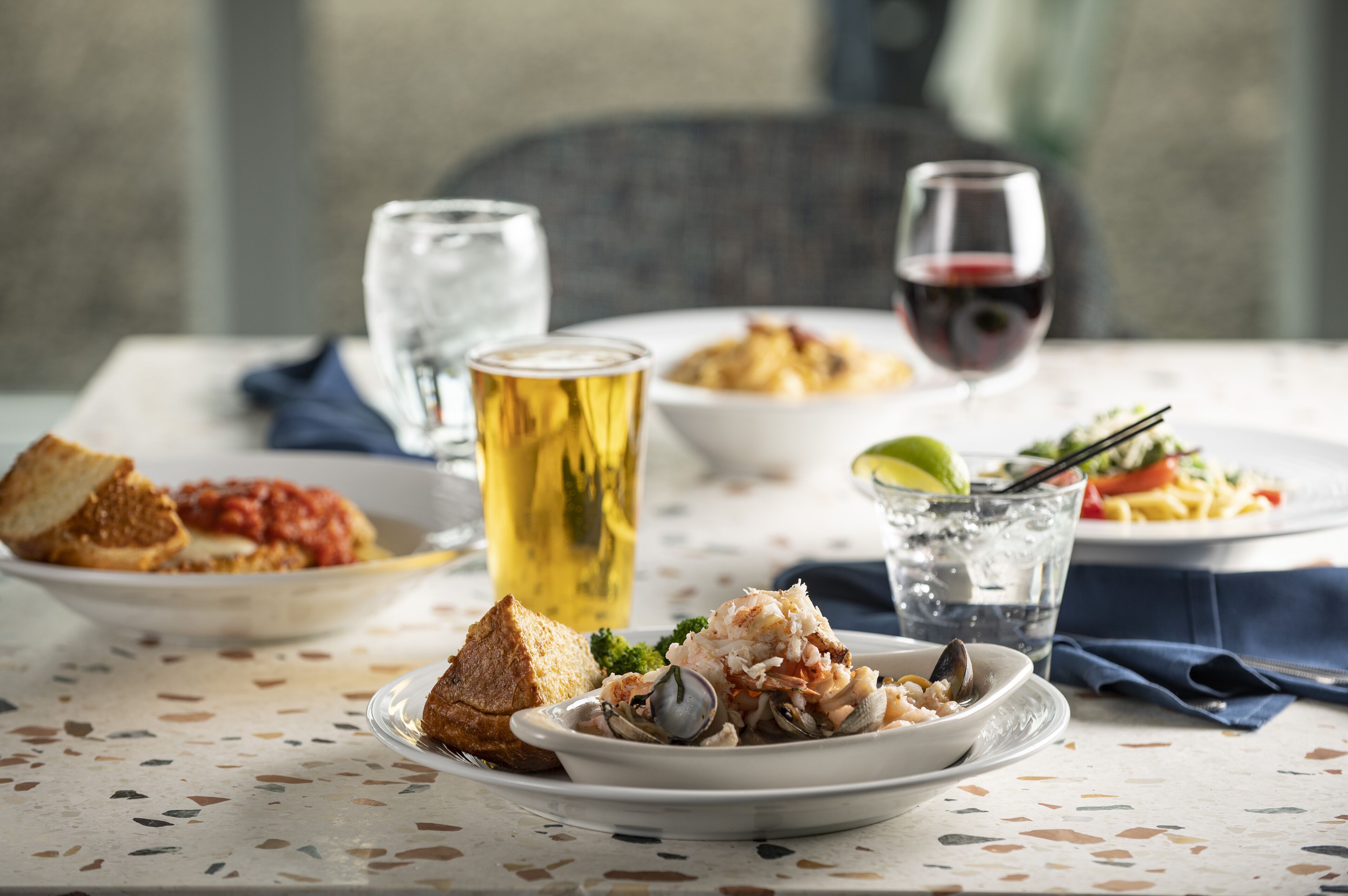 A dining table with various dishes, including seafood, bread, and a glass of wine.