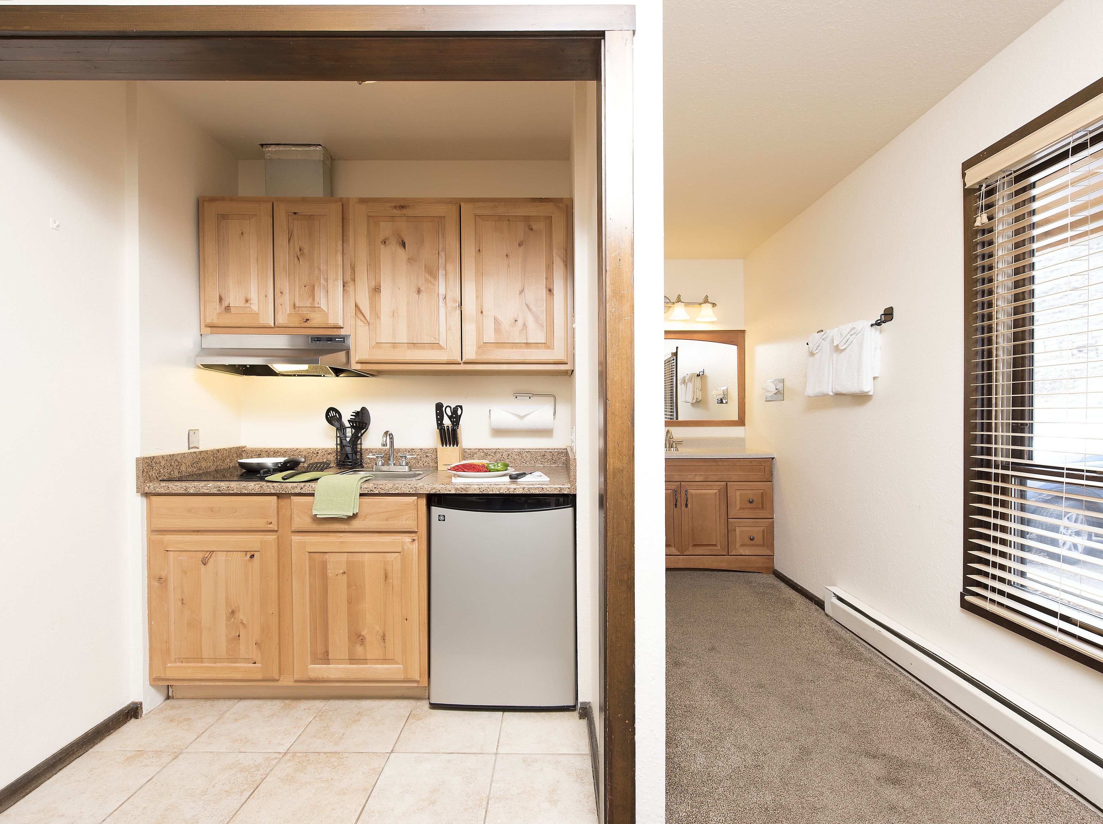 A compact kitchen with wooden cabinets, a dishwasher, and a countertop with various kitchen utensils.