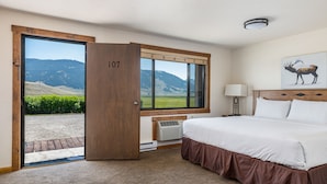 Ett hotellrum med en stor säng, ett fönster med utsikt över bergen och en dörr med skylten "107".