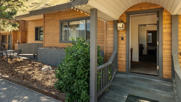 Ett trähus med en inglasad veranda, en mur av tegelsten och ett fönster.