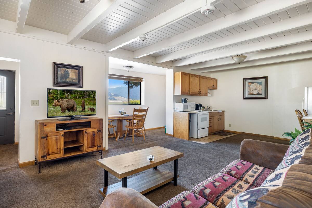 A living room with a wooden entertainment unit, a sofa, and a dining area with a view of the outdoors.