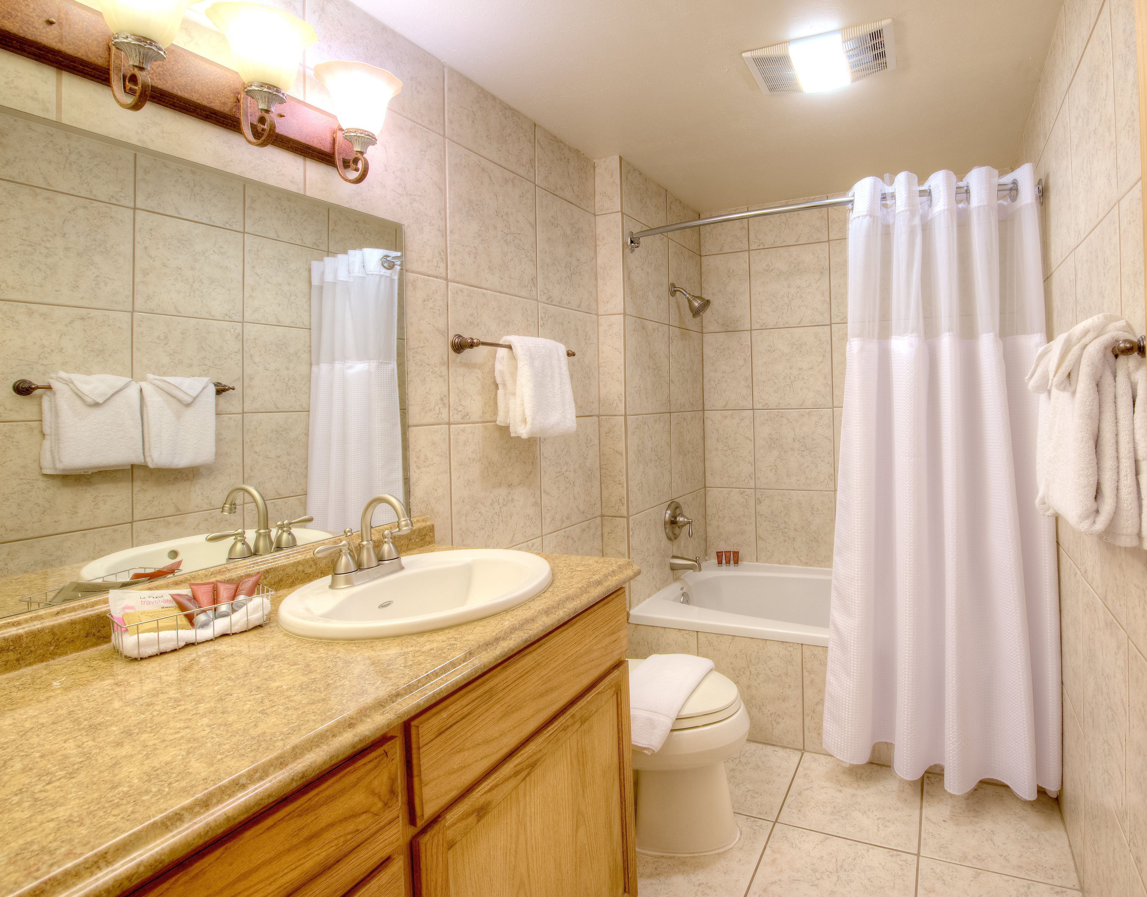 Une salle de bain équipée d’un lavabo, d’un miroir, d’un porte-serviettes, d’une douche et de toilettes.