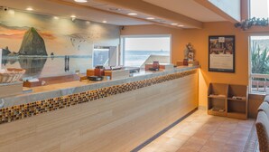 A reception area with a view of the ocean, a tiled backsplash, and a framed menu on the wall.