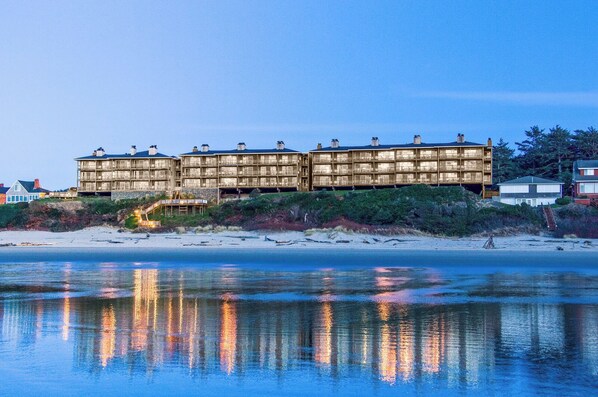 A beachfront hotel with multiple floors, balconies, and a sandy beach in the foreground. - Hallmark Resort - Cannon Beach (Cannon Beach)