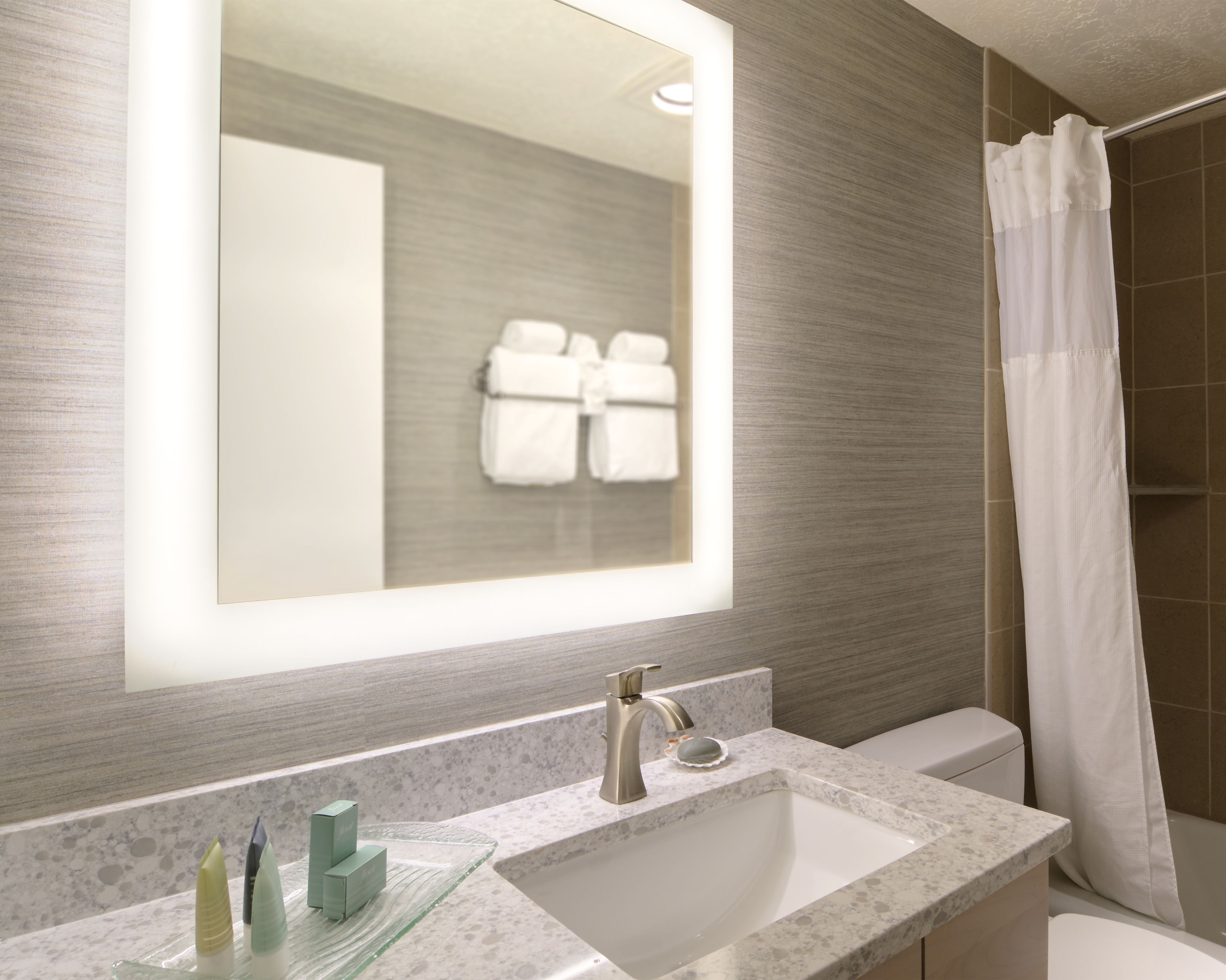 A modern bathroom with a large mirror, a sink, and a shower area.