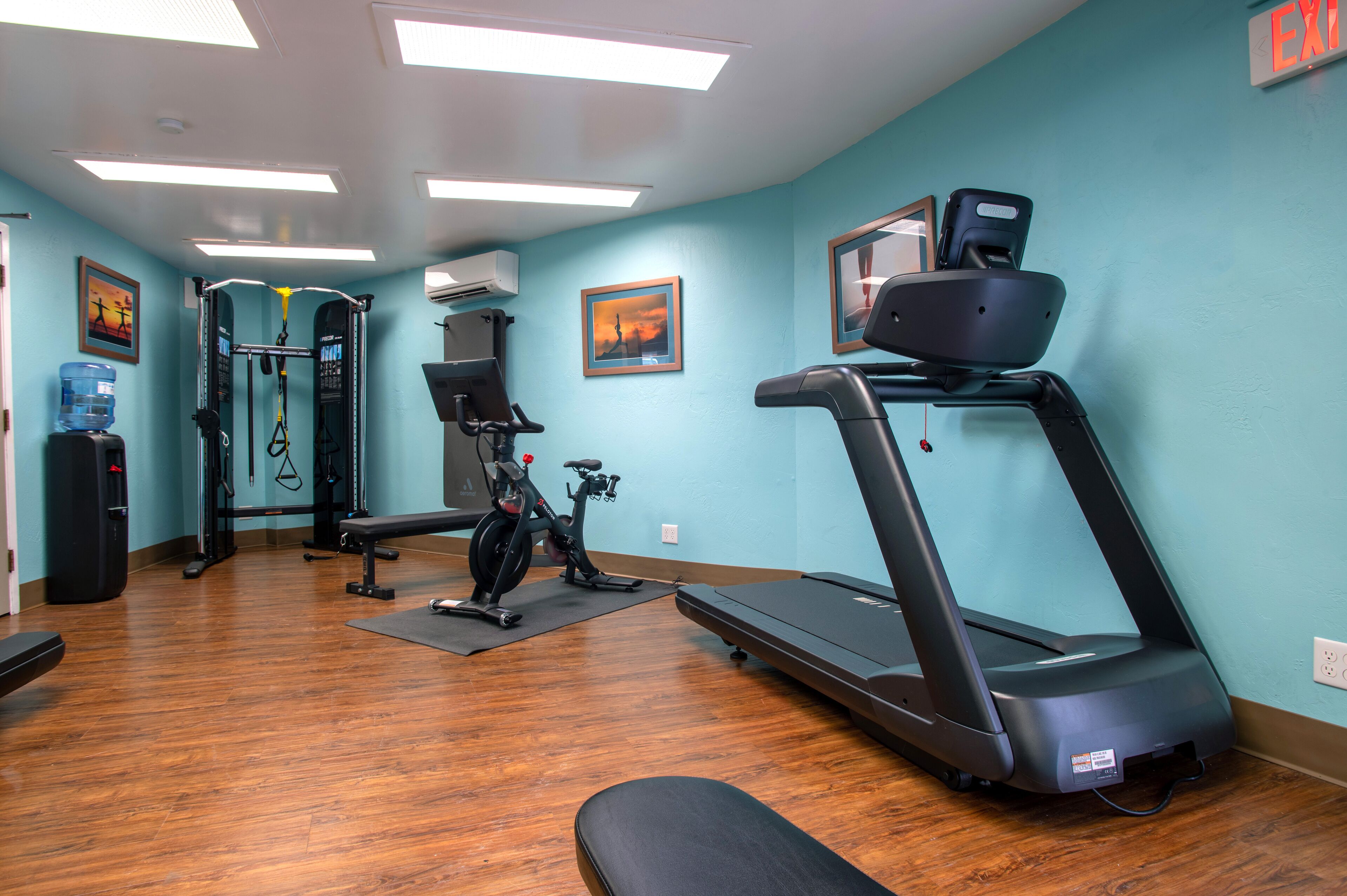 Een sportschool met een loopband, een hometrainer en krachttoestellen.
