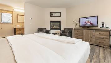 A hotel room with a large bed, a desk with a chair, a television, and a cabinet.