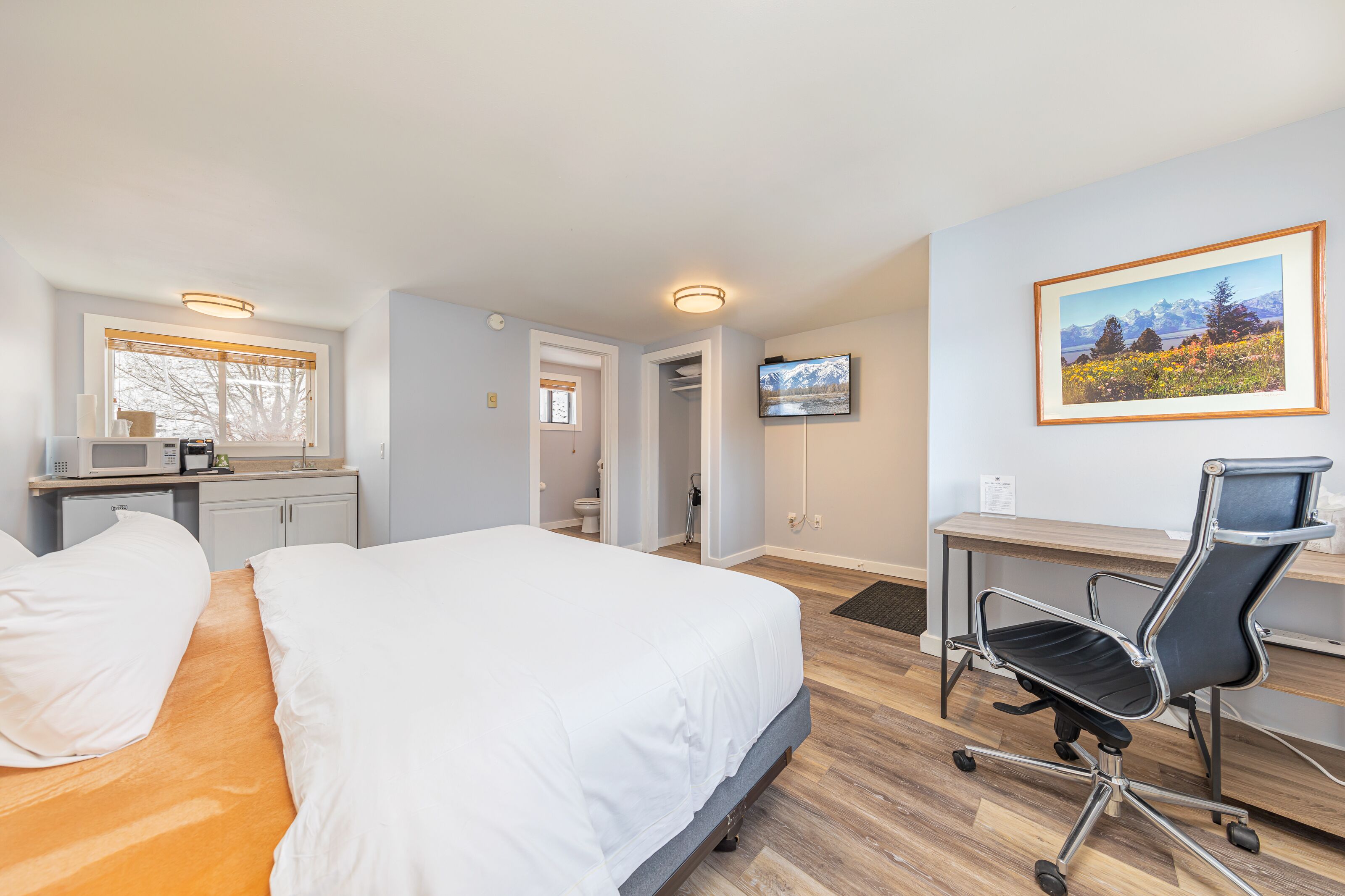 Une chambre d’hôtel avec un lit, un bureau et un téléviseur fixé au mur.