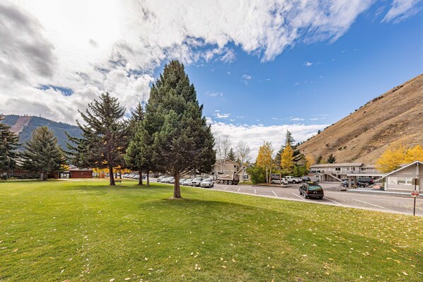 A parking lot with several cars, a grassy area with trees, and buildings in the background. - Miller Park Lodge (Jackson)