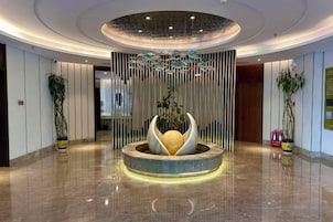 A modern lobby with a central water feature, vertical light fixtures, and potted plants.