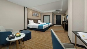 A hotel room with a bed, a desk, a chair, and a small table with a fruit bowl. - Ready Hotel (Taiyuan)