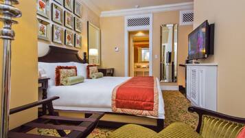 A hotel room with a large bed, a TV, a desk, and a chair.