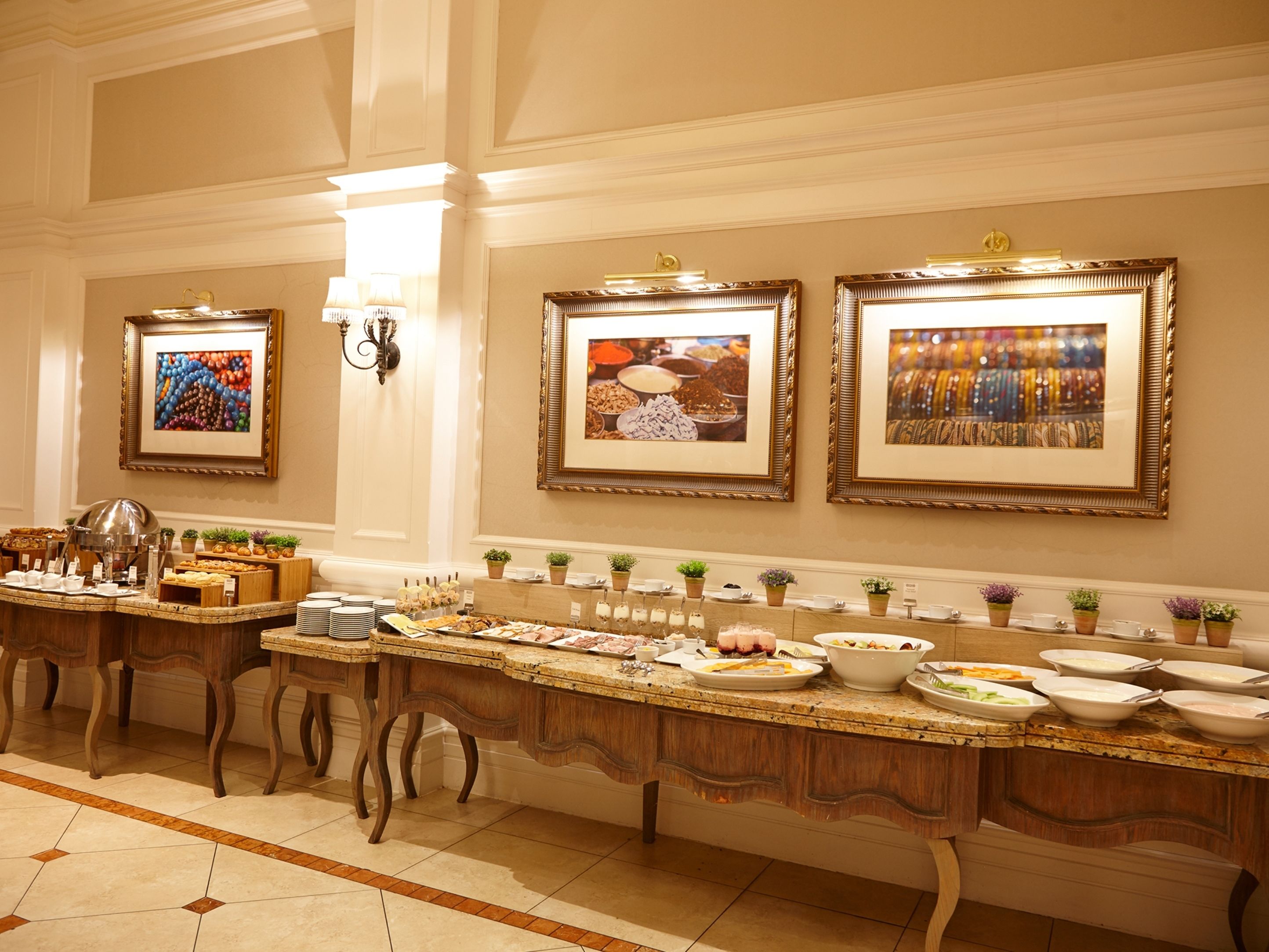 Una larga mesa de buffet con diversas opciones de comida y una estación de café, fotografías enmarcadas en la pared y un candelabro.
