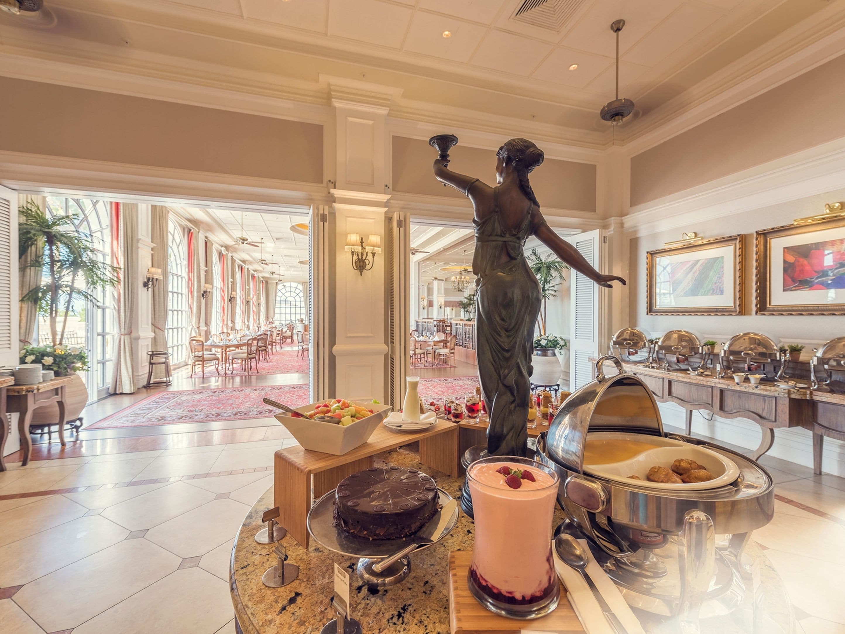 En stilfuld lobby med en marmorindretning ved receptionen, en statue og et buffetområde med et udvalg af mad.