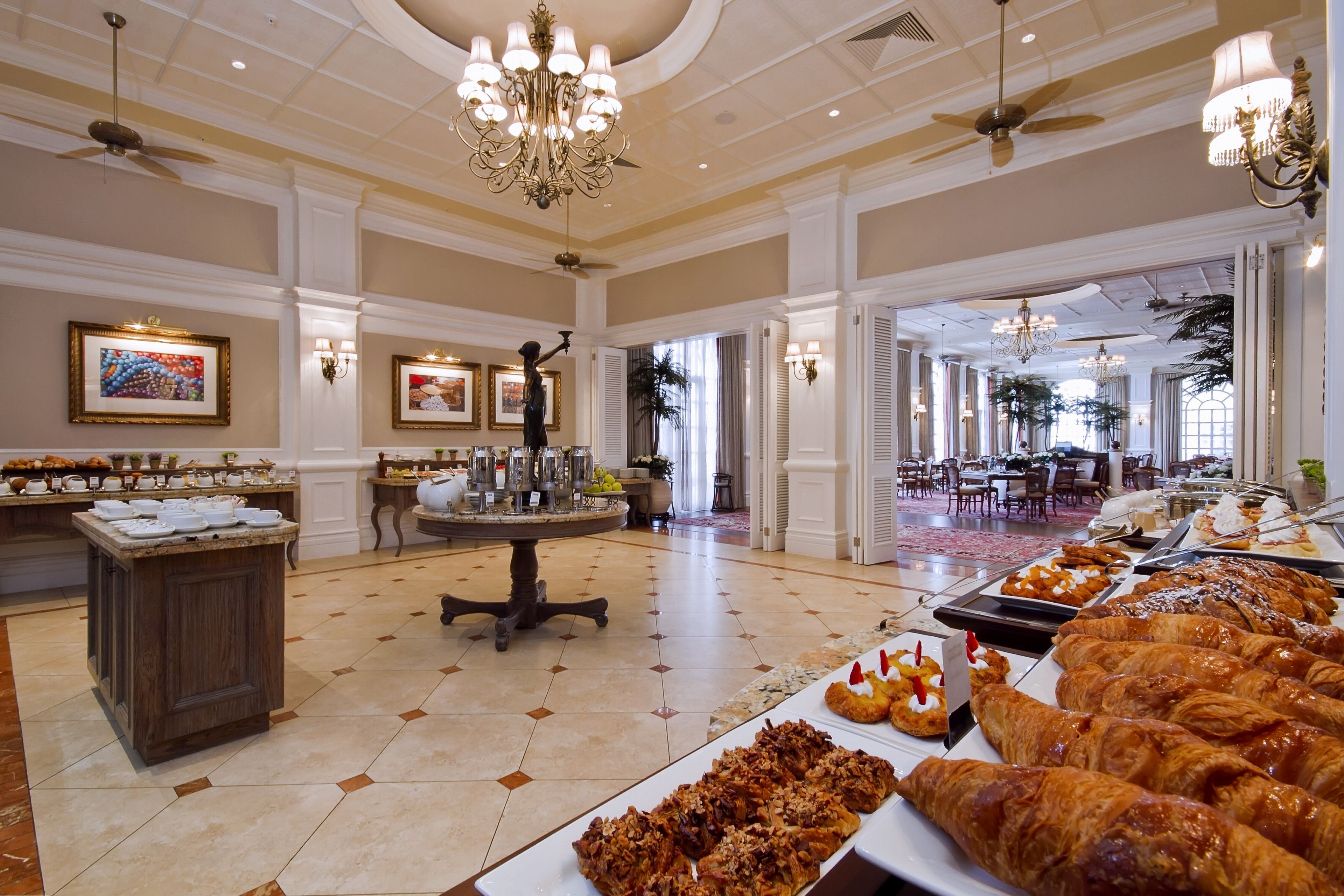 Um amplo saguão de hotel com área de buffet, oferecendo doces e um espaço para café.