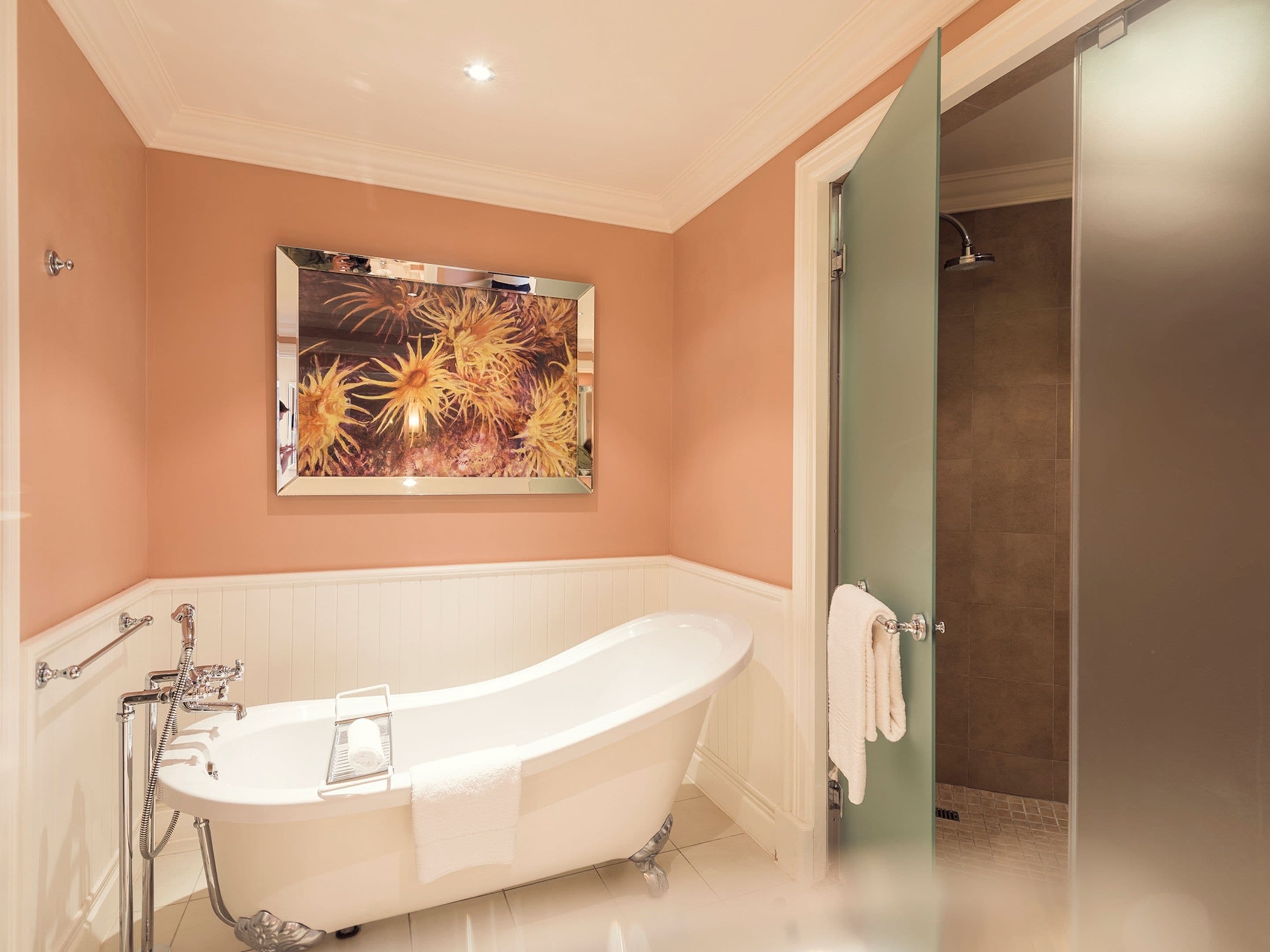 A bathroom with a freestanding bathtub, a shower, and a wall-mounted artwork.