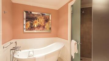 A bathroom with a freestanding bathtub, a shower, and a wall-mounted artwork.