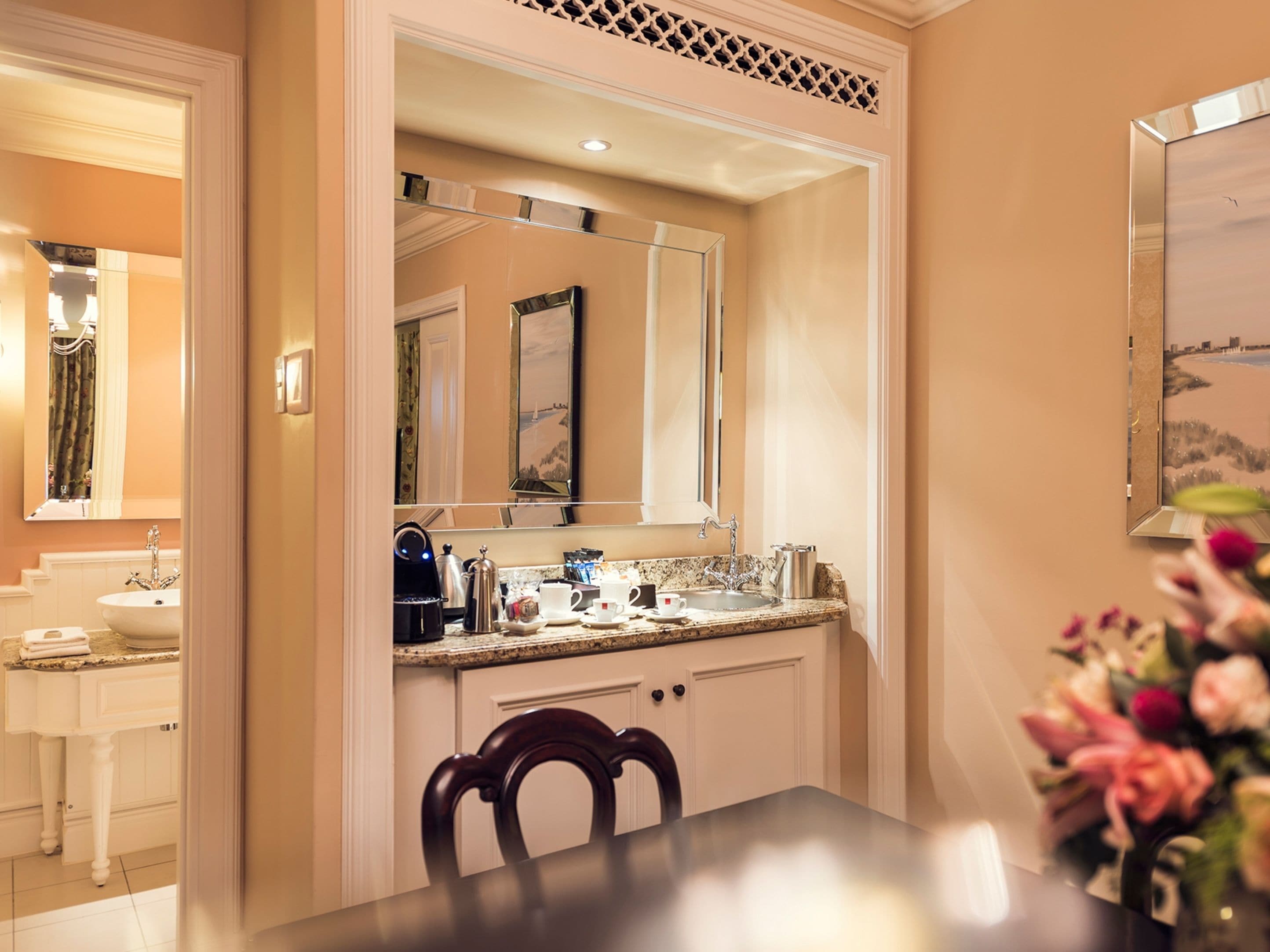 A hotel bathroom with a sink, mirror, and a view of the beach through the window.