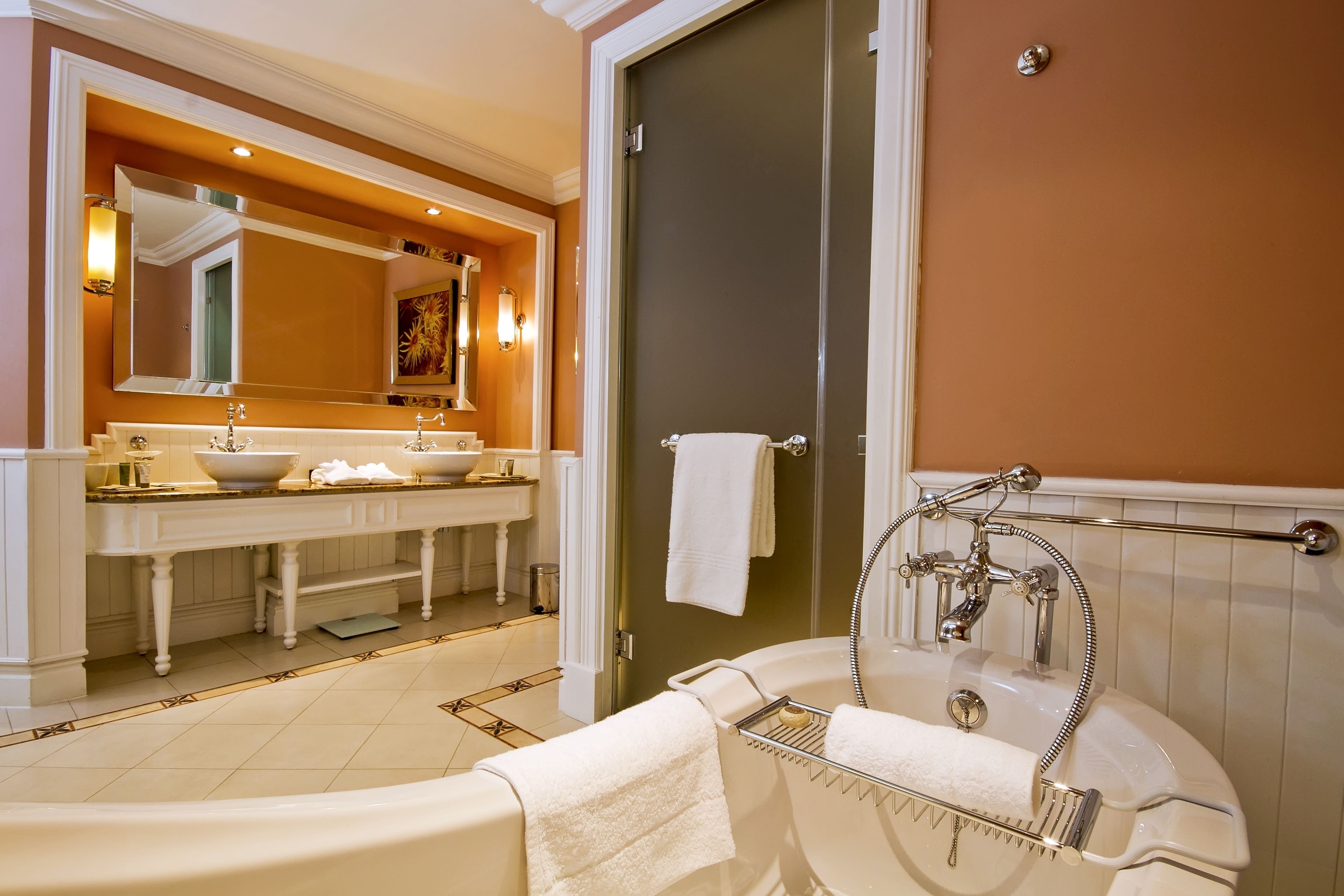 Un baño con bañera, lavamanos con espejo y ducha.
