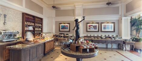 A spacious hotel lobby with a central round table, a coffee station, and a statue.