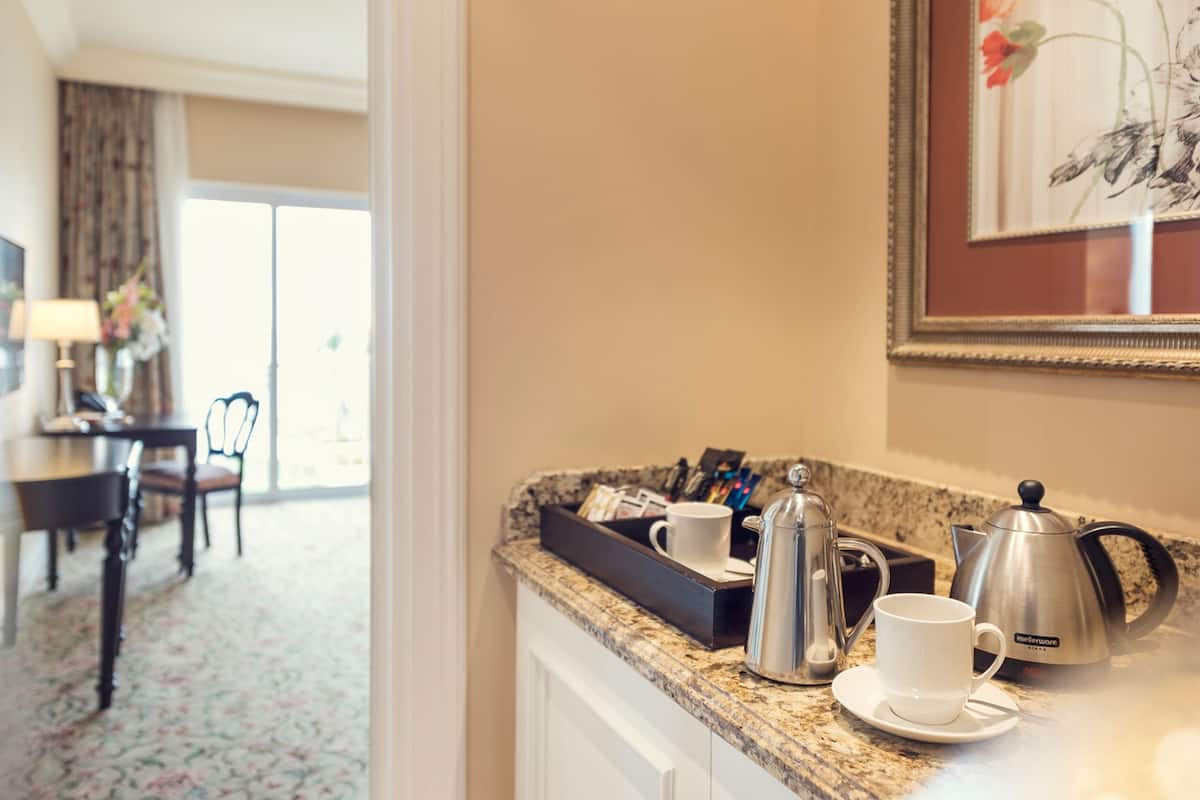 Una cocina de hotel con una cafetera, un hervidor y una bandeja con tazas.