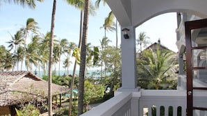 A balcony with a view of a tropical resort, including palm trees and a beach. - MUINE SUN & SEA BEACH ( BOUTIQUE RESORT & GLAMPING) (Mui Ne)