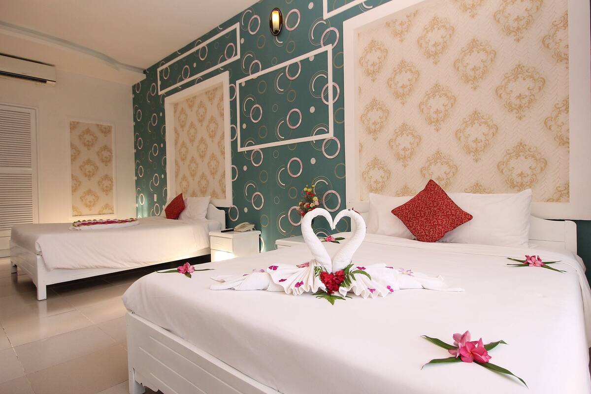 Une chambre d’hôtel avec deux lits, un mur décoratif et une disposition des serviettes en forme de cœur.