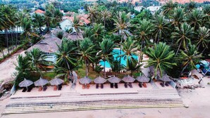 A resort with a beach, palm trees, and a swimming pool. - MUINE SUN & SEA BEACH ( BOUTIQUE RESORT & GLAMPING) (Mui Ne)