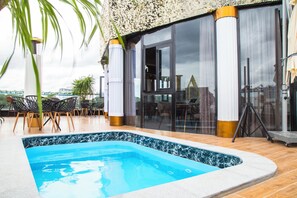 Una piscina con borde de azulejos, rodeada por un patio con sillas y una mesa.