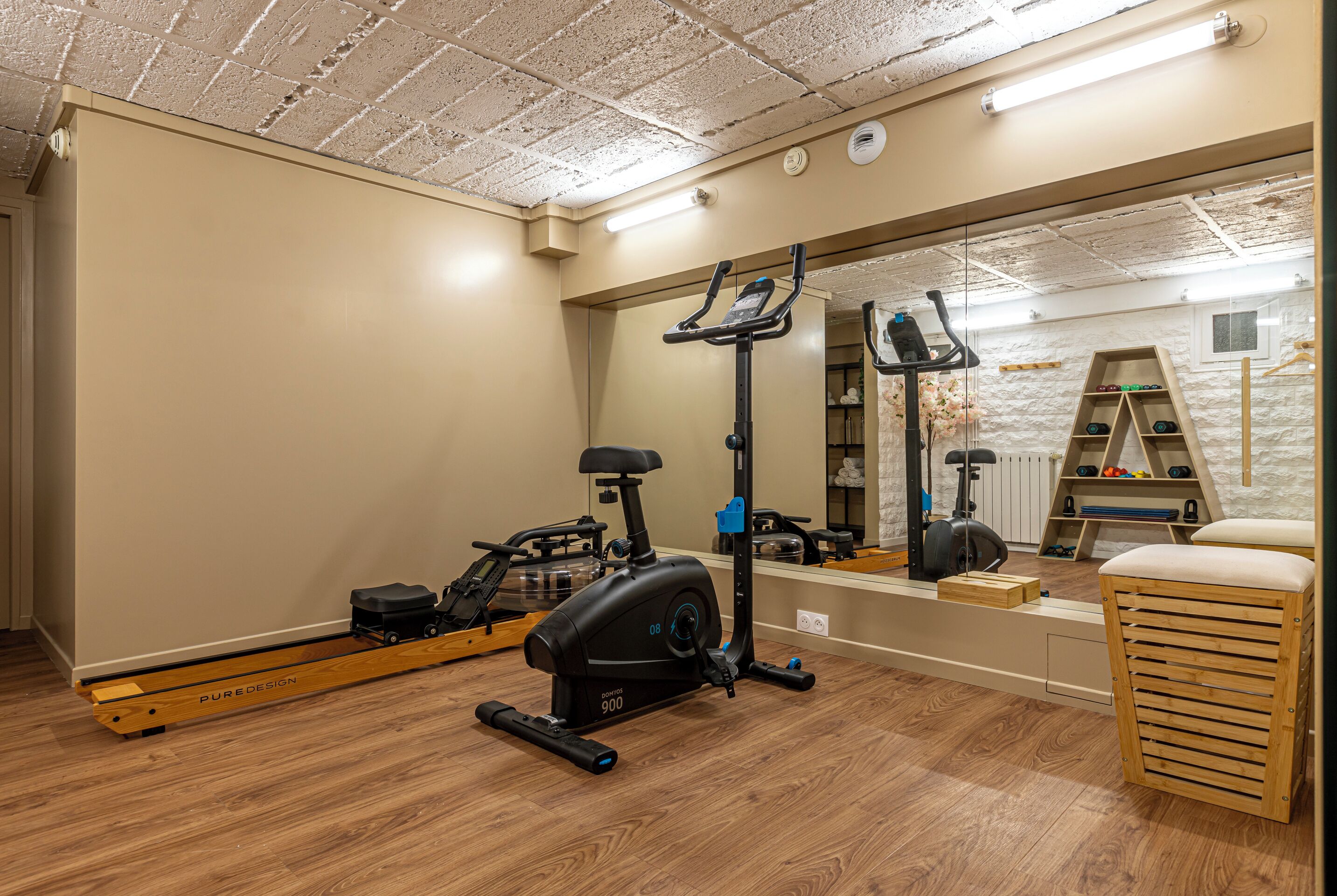 A home gym with exercise equipment, a mirror, and a wooden bench.