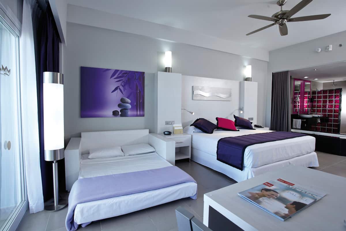 Una habitación de hotel moderna con dos camas, una sala de estar y un comedor.