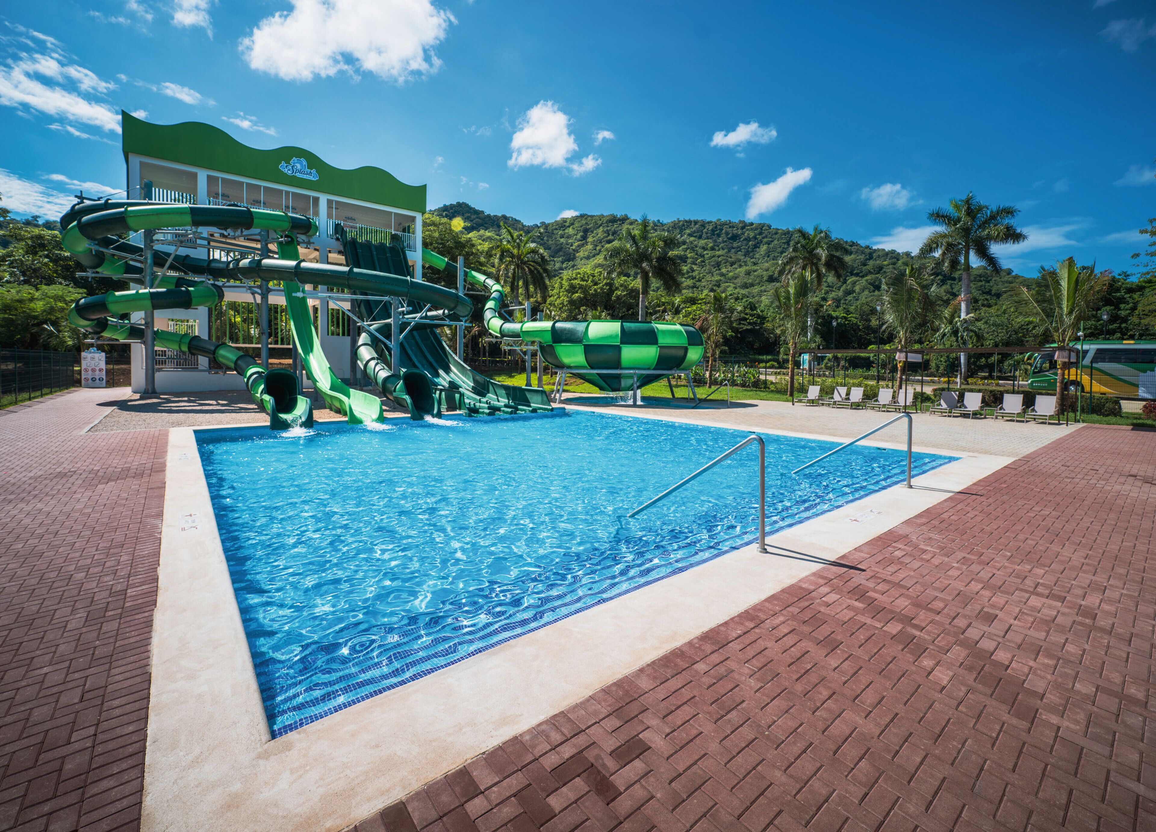 Una piscina con tobogán y un edificio con un letrero.