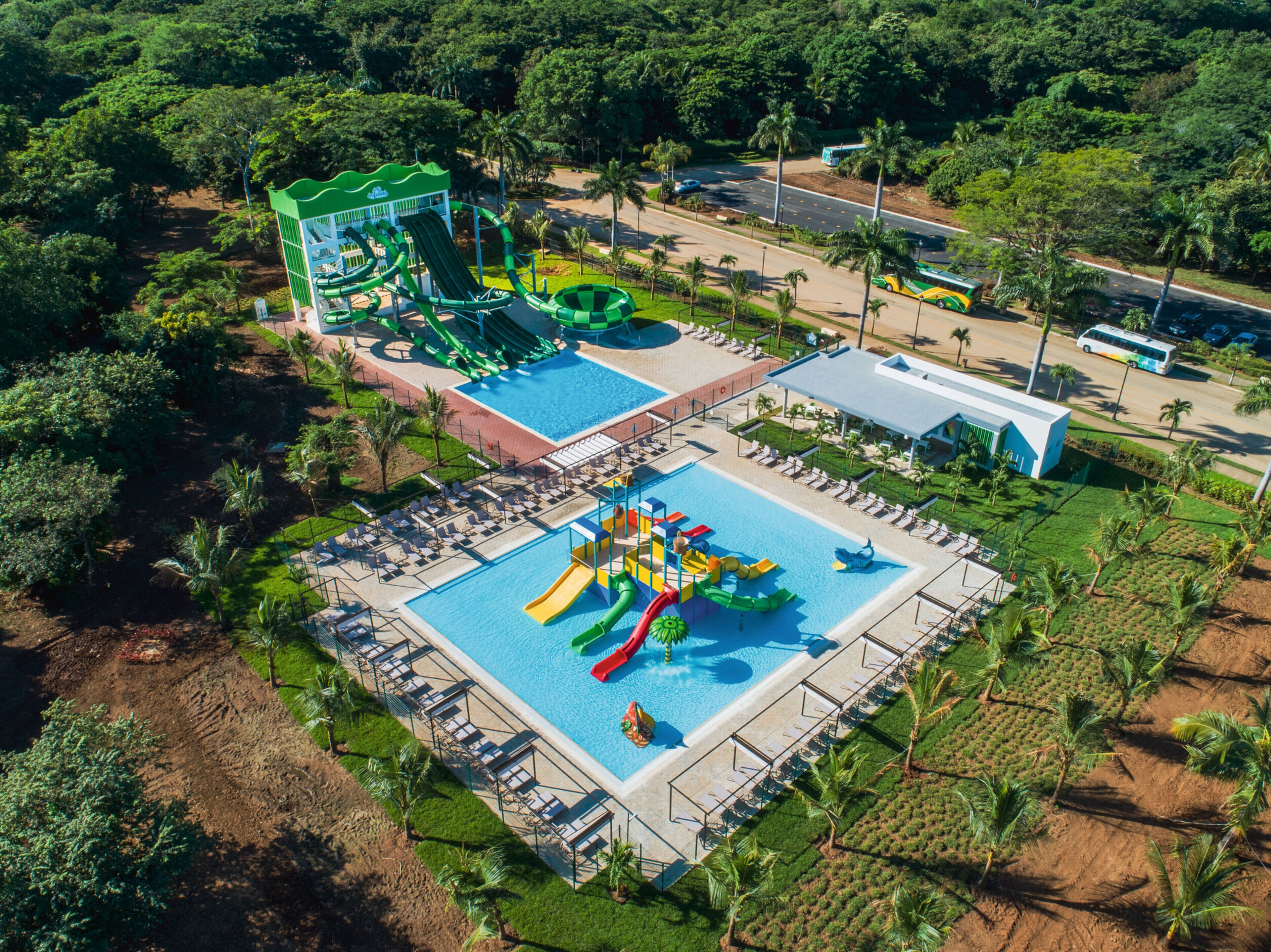An aerial view of a resort with a large pool area, a water park, and a bus service.