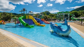 A swimming pool with multiple slides and a dolphin float.