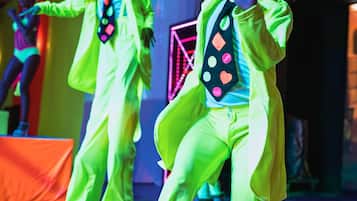A stage with performers in bright yellow outfits and hats.