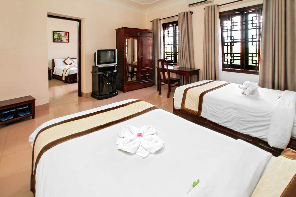 A hotel room with two beds, a desk, a television, and a wardrobe.